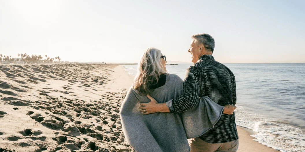 Older couple walking arm in arm along a beach