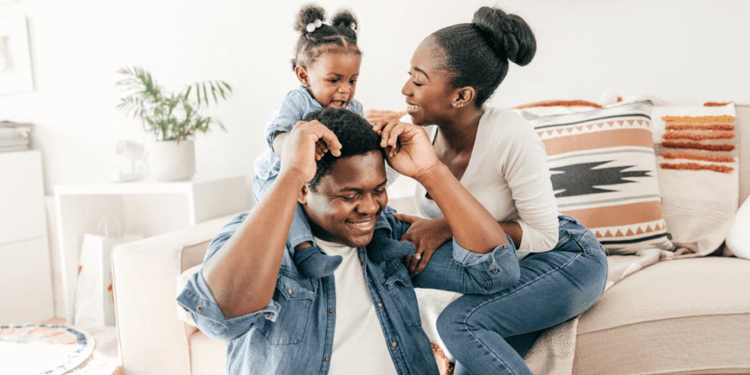 Parents playing with their young daughter on a living room couch