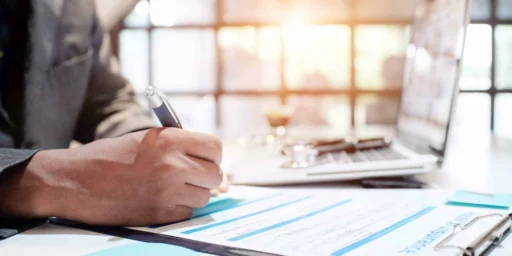 Businessperson reviewing charts and signing documents at a desk