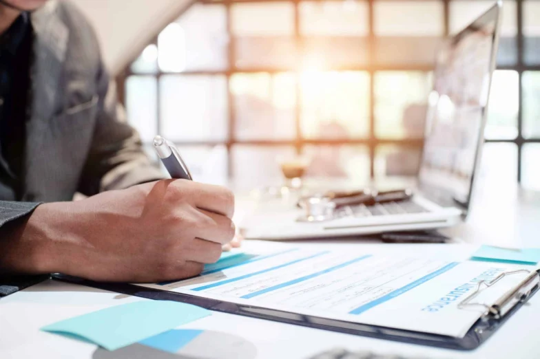 Businessperson reviewing charts and signing documents at a desk
