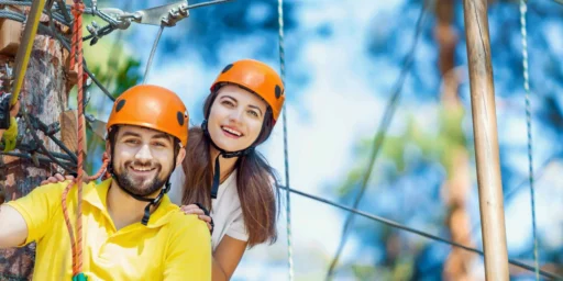 Smiling couple wearing orange safety helmets on a ropes course