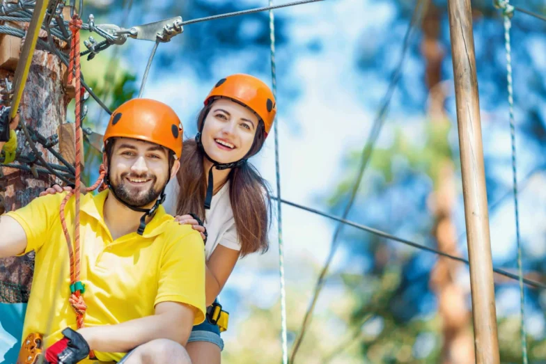 Smiling couple wearing orange safety helmets on a ropes course