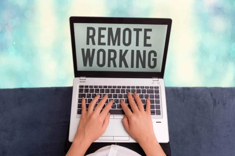 Hands typing on a laptop displaying the words Remote Working