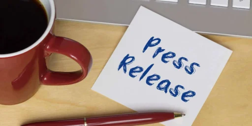 Note reading Press Release beside a coffee mug and pen