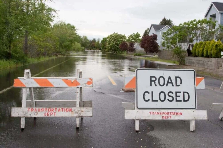 Road closed barricades in front of a flooded residential street