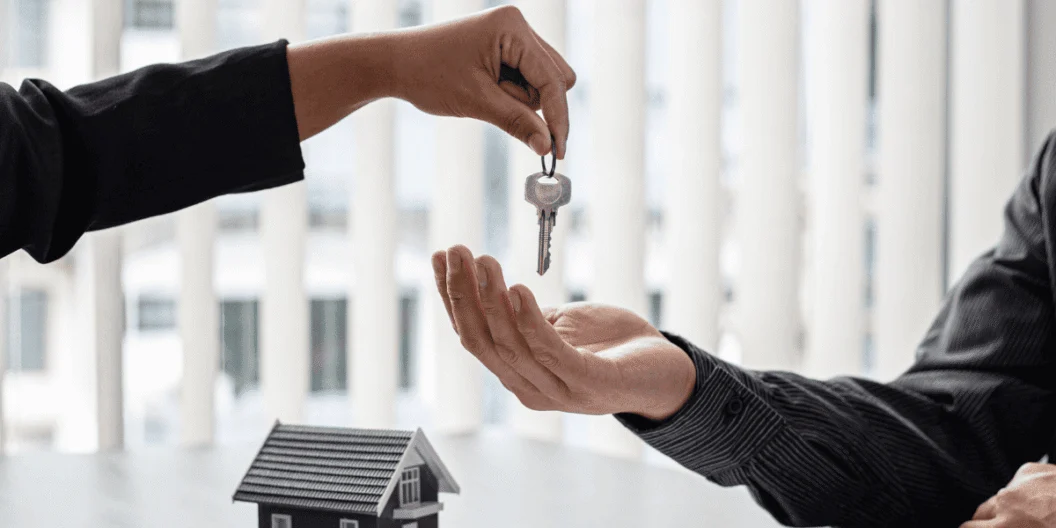 One person handing another person a key to a house