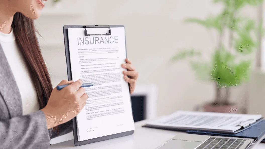 Person pointing to an insurance form on a clipboard