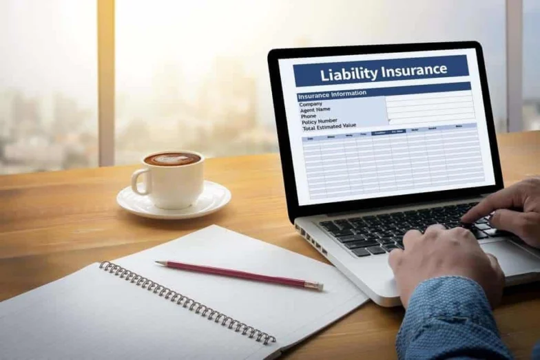 Laptop showing a liability insurance form beside a coffee cup and notebook