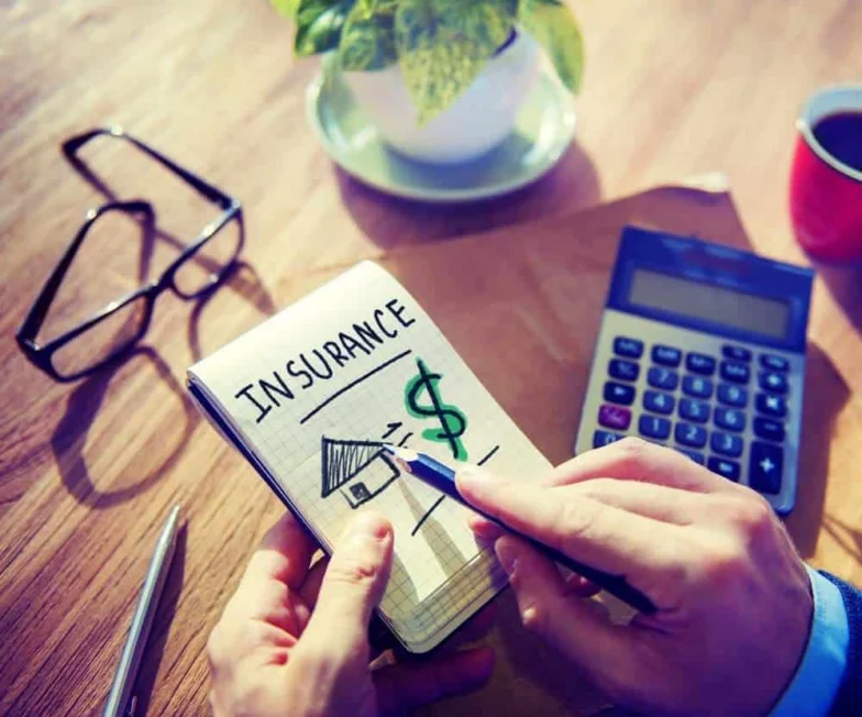 Person calculating insurance costs with a notepad and calculator