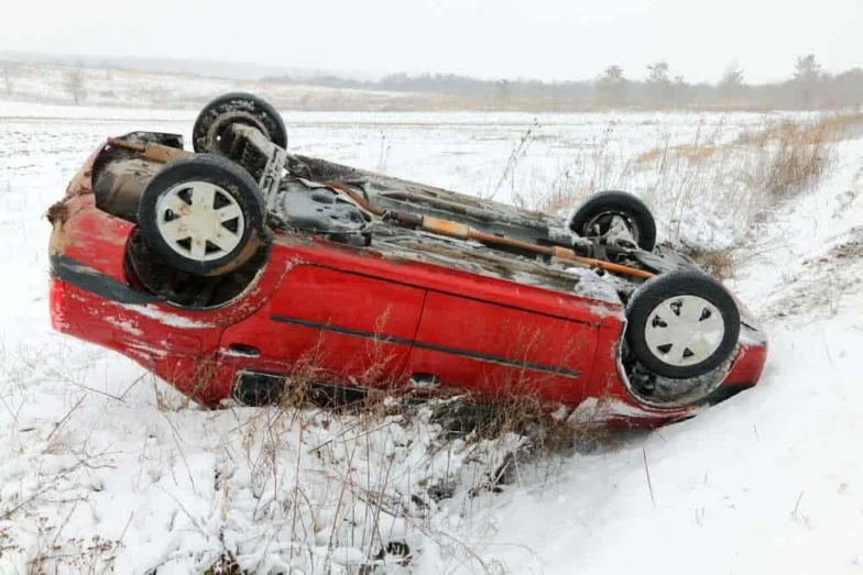 Red car overturned in a snowy field