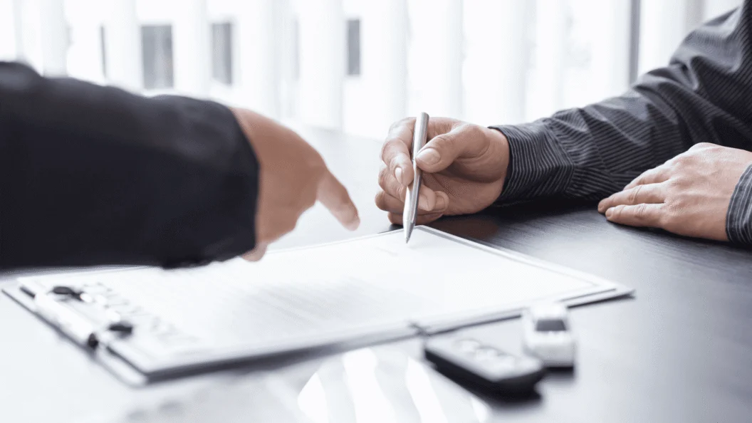 Two people signing a document on a clipboard